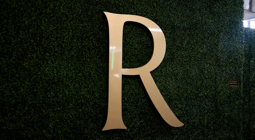 signage showing the letter R over greenery